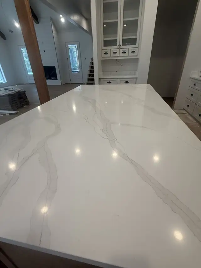 Long kitchen island with a polished white countertop and bold gray veining