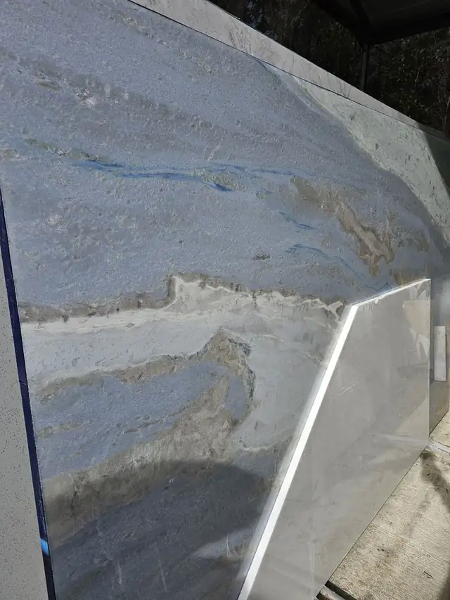 Close view of a natural stone slab with blue and taupe veining