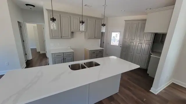 Kitchen with gray shaker cabinets, white veined countertops and a peninsula with a double sink